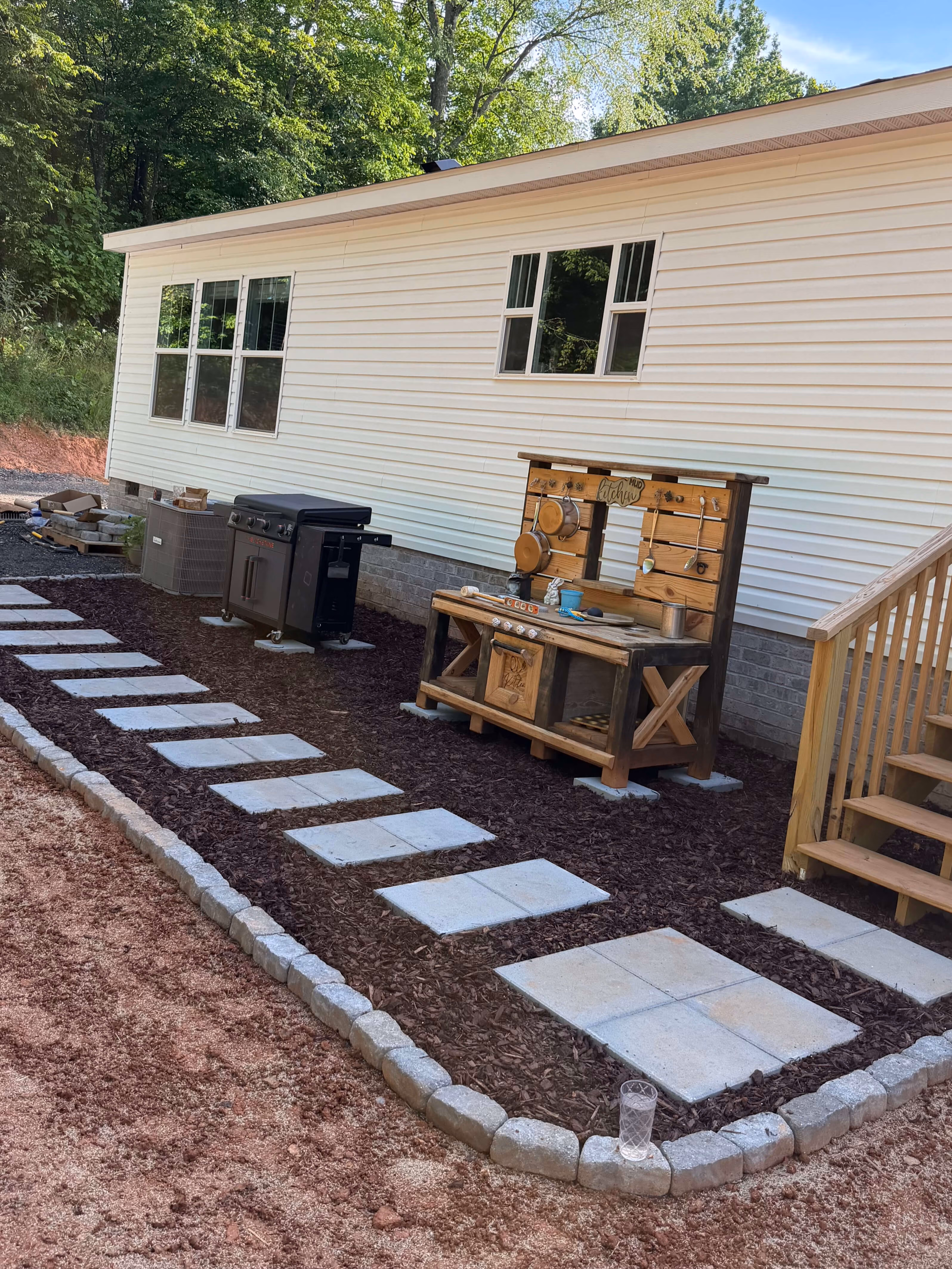 Stone pathway with mulch edging leading to porch stairs of a brick house with a Mickey Mouse birdbath and a CPI security sign in the grass.